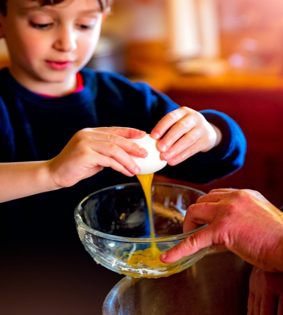 Toddler chef helping with an egg for baking